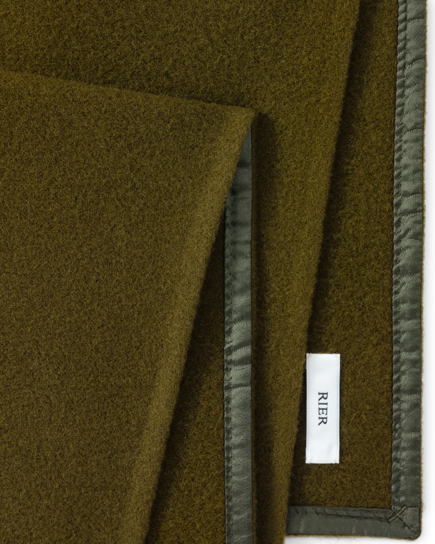RIER wool fleece scarf in Soil olive green, close-up of the finished edge and woven label