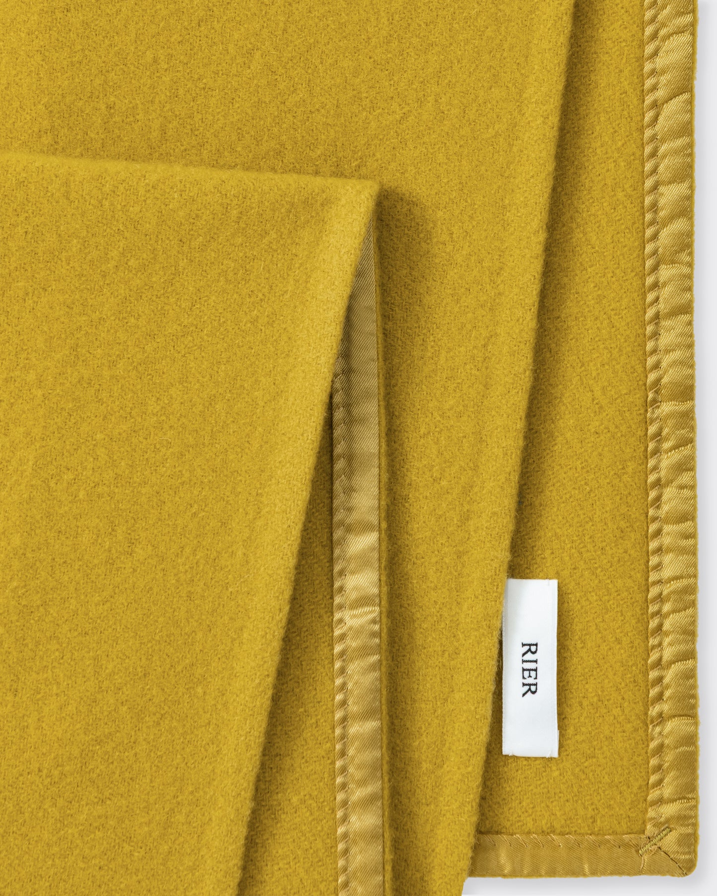 RIER wool fleece scarf in Wax mustard yellow, close-up of the finished edge and woven label
