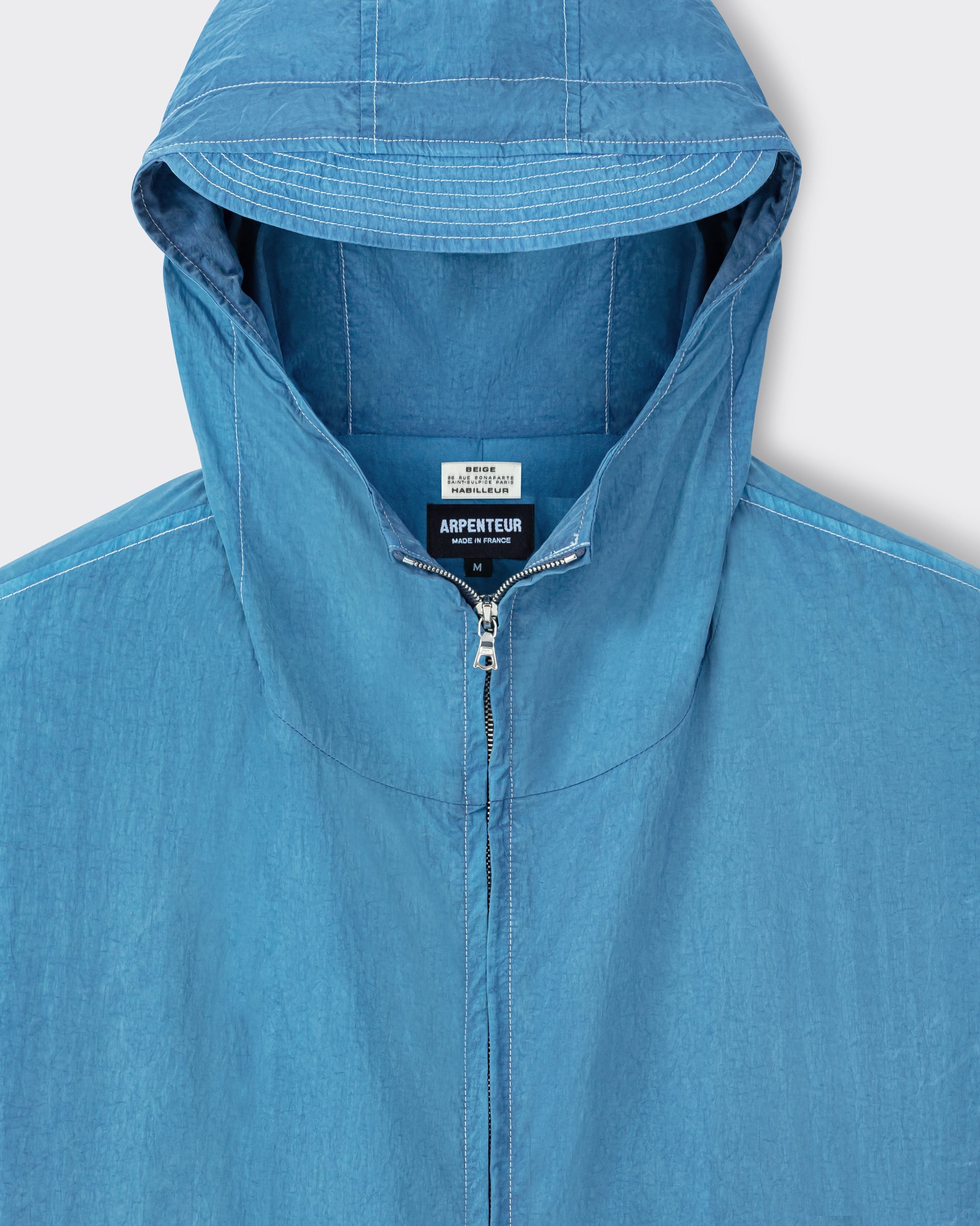 Arpenteur Kaolin nylon jacket in pastel detail of fixed hood and two-way zip at Beige Habilleur Paris