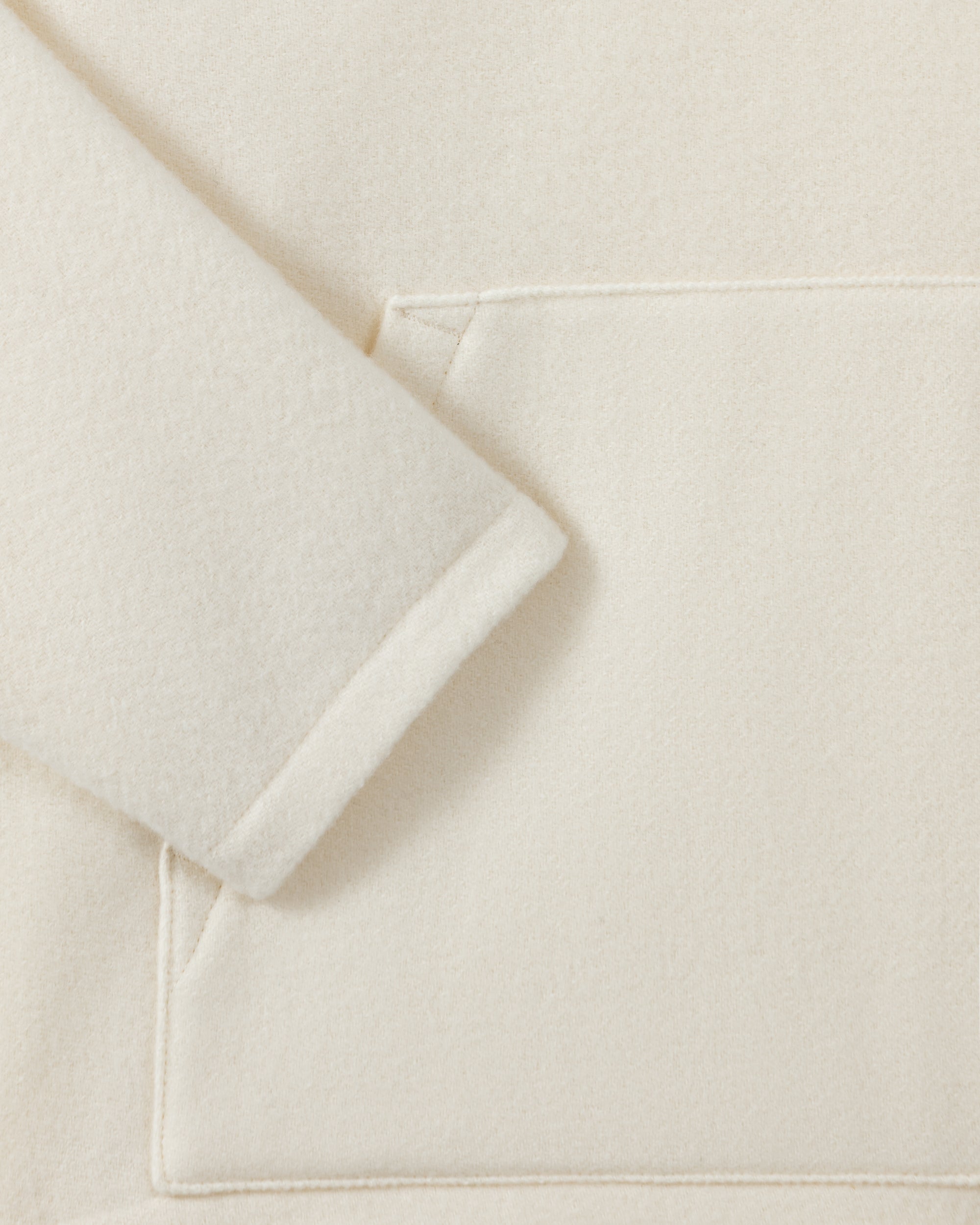 RIER hooded wool fleece in white, close-up of the sleeve and natural wool fleece texture