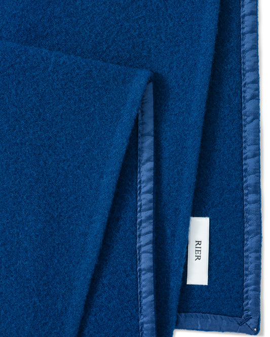 RIER wool fleece scarf in indigo blue, close-up of the finished edge and woven label