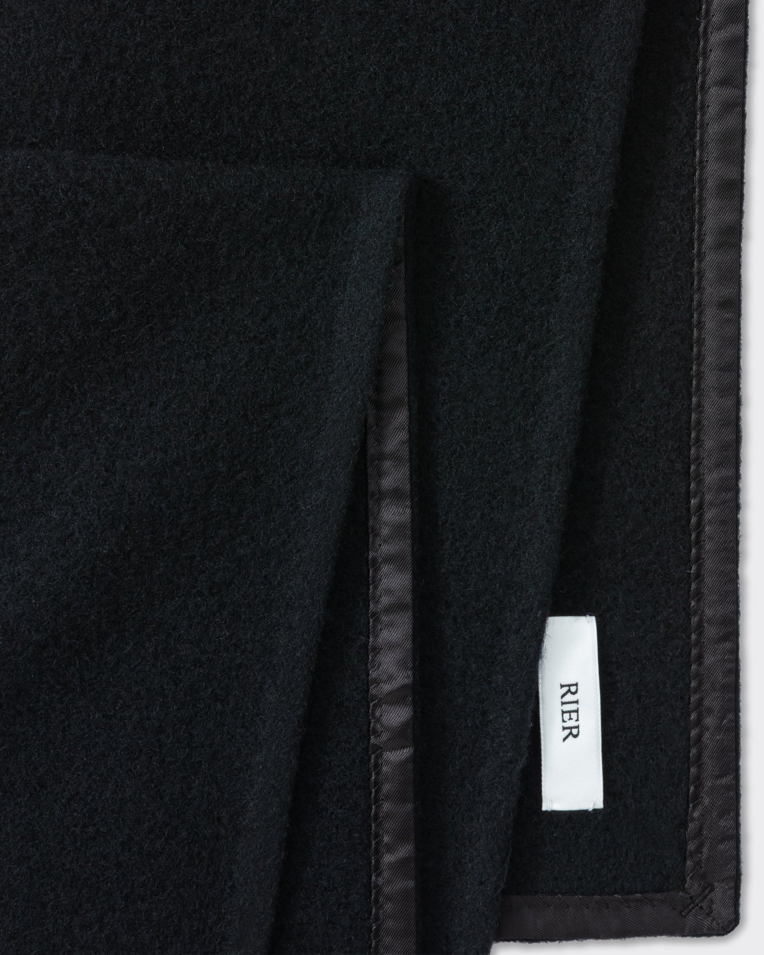 RIER wool fleece scarf in black, close-up of the finished edge and woven label