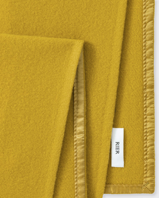 RIER wool fleece scarf in Wax mustard yellow, close-up of the finished edge and woven label